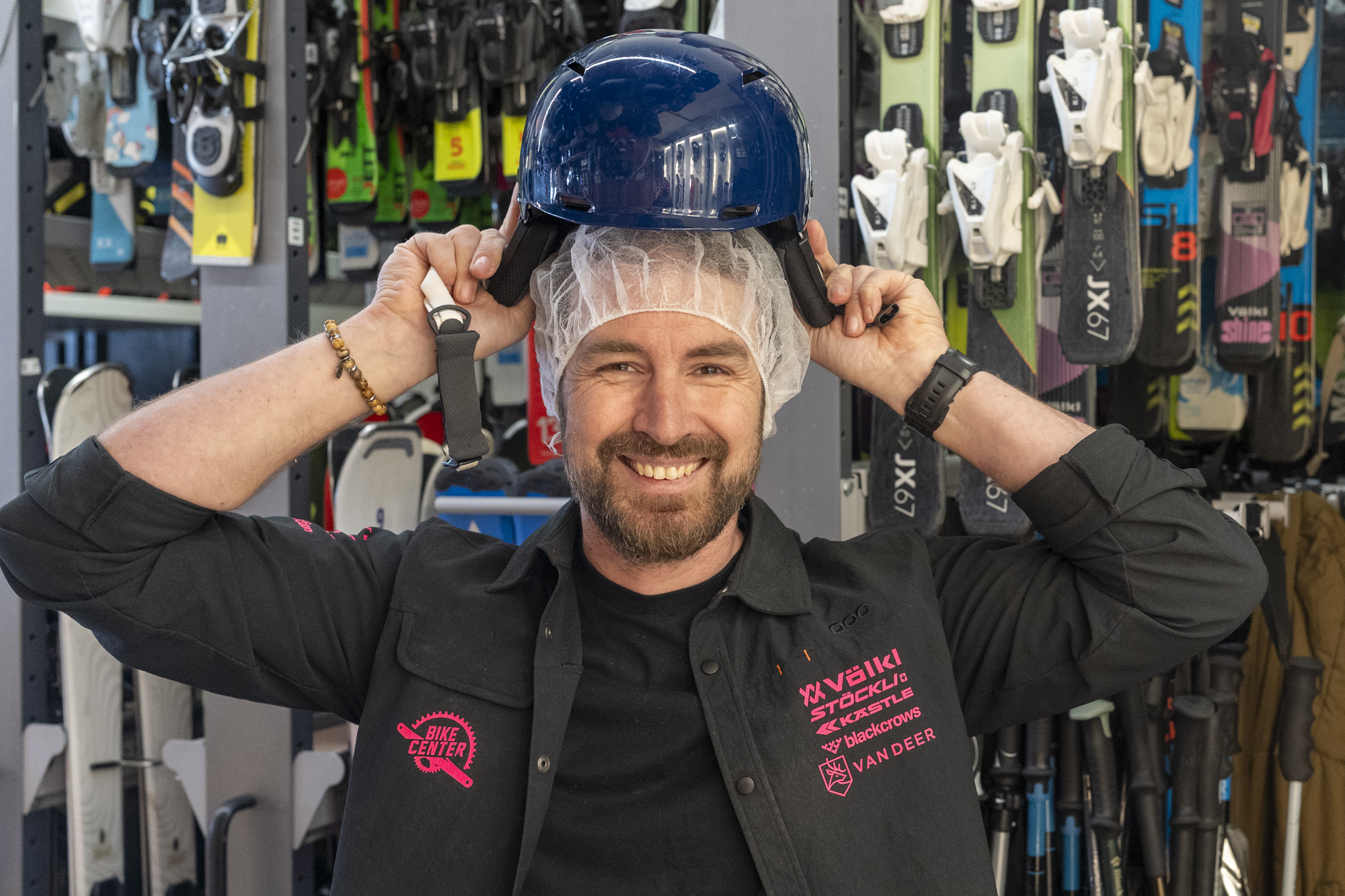 A smiling customer tries on a clean ski helmet at SKI CENTER